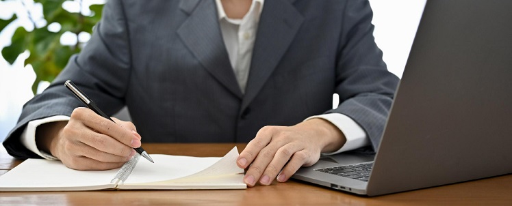 une femme avec un ordinateur et écrivant sur un cahier