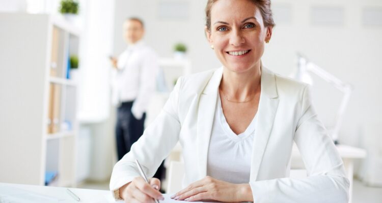 une femme souriante assise sur son bureau