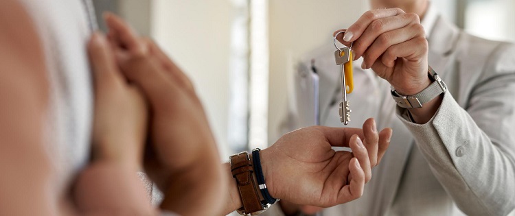 une femme agent immobilier donnant les clés d'un bien immobilier à des clients