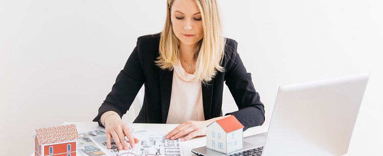 une juene femme agent immobilier regardant des plans immobiliers