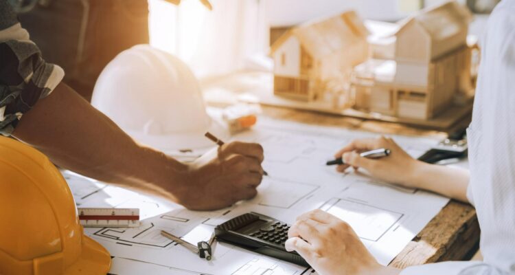 des professionnels de l'immobilier discutant devant des plans de construction