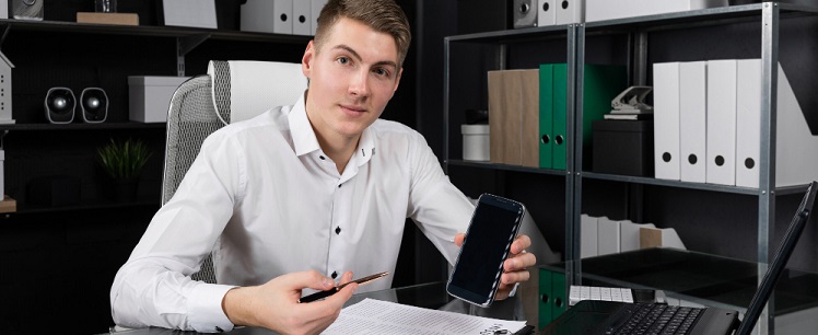 un homme travaillant et montrant son téléphone portable