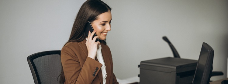 une assitante de direction assise à son bureau et au téléphone