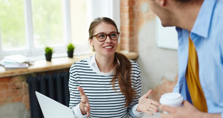 une assistante de direction souriante et discutant avec un collègue