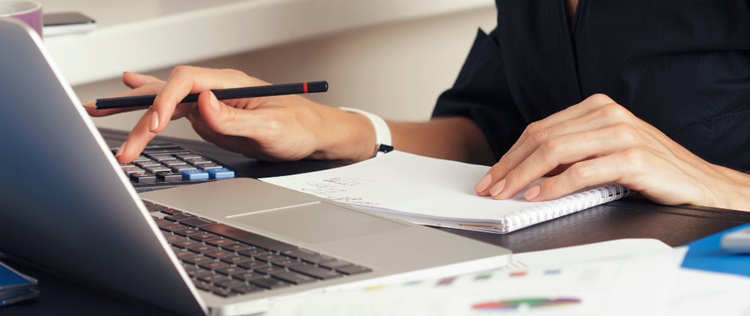 une femme avec un cahier devant son ordinateur portable