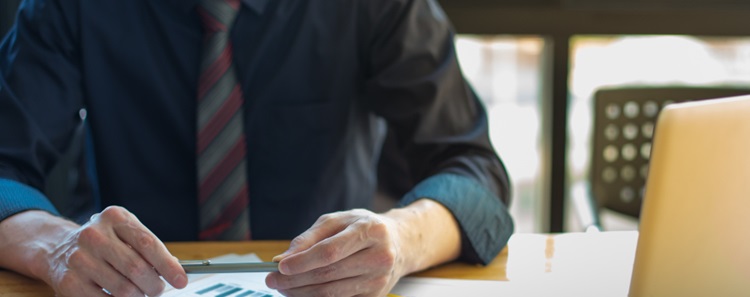 une personne tenant son stylo assis à son bureau