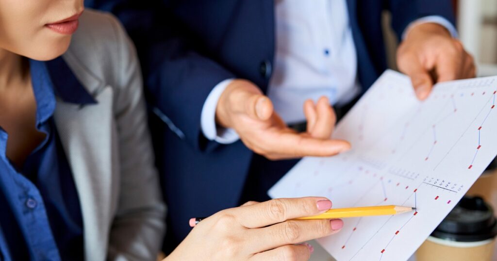 une jeune femme montrant des chiffres avec son crayon papier à une autre personne