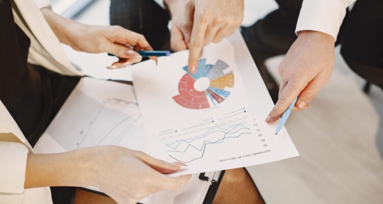 des personnes montrant du doigts un graphique de chiffres