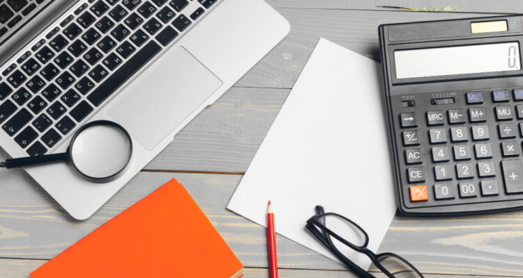un ordinateur, une calculatrice et des outils de comptabilité posés sur un bureau