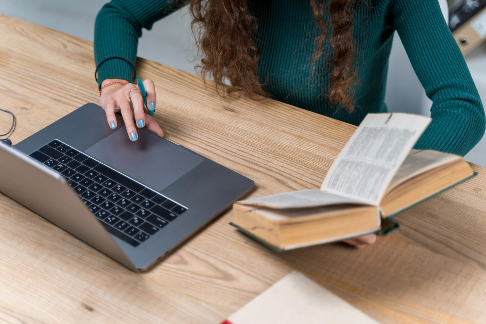 une femme travaillant derrière son ordinateur avec un livre juridique