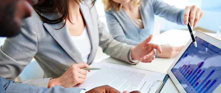 3 personnes discutant autour de chiffres financiers